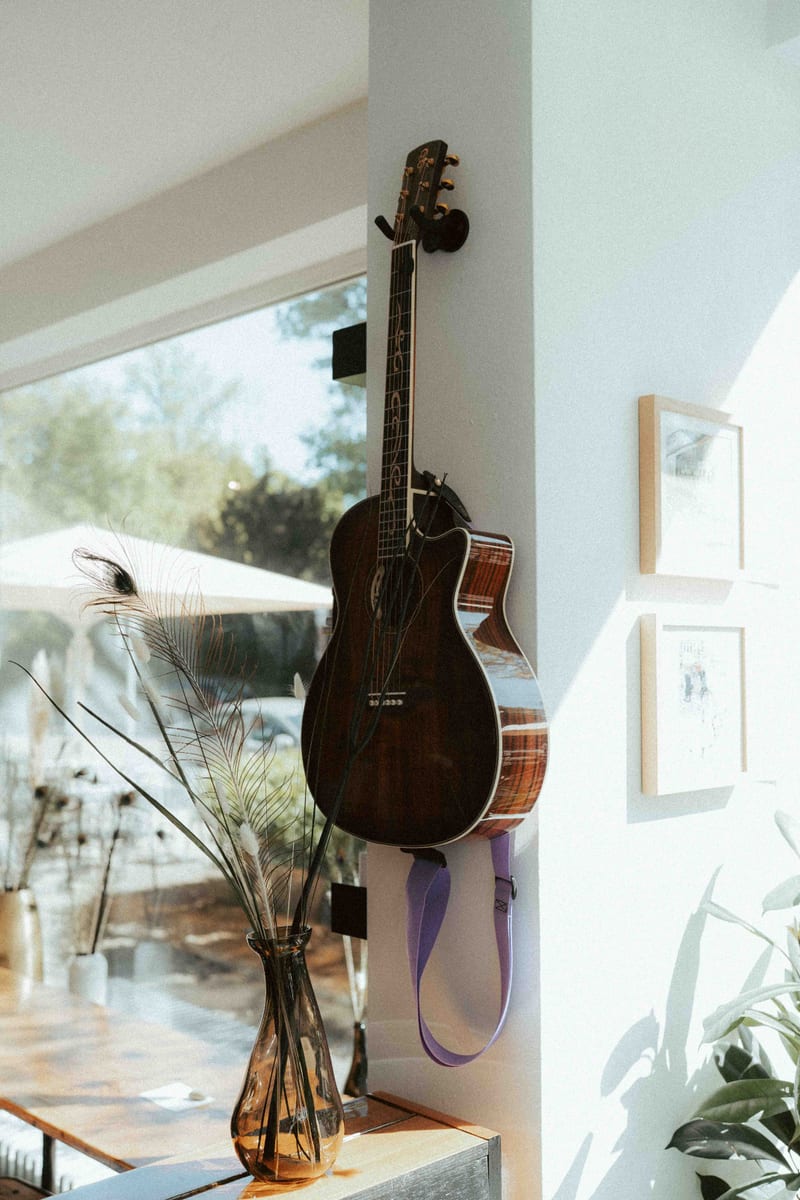 Gitarre an der Wand mit Pflanzen und Bilderrahmen